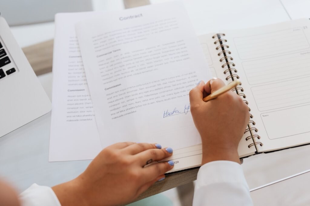Manos de una persona firmando un documento sobre un escritorio